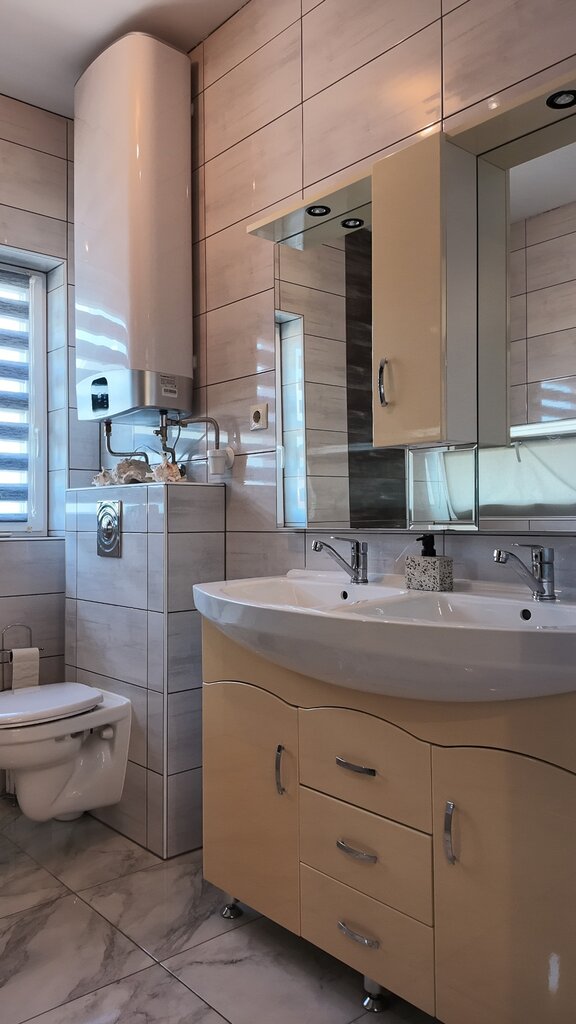 Fürdőszoba beépített bútorokkal, fali WC-vel és tükrös szekrénnyel